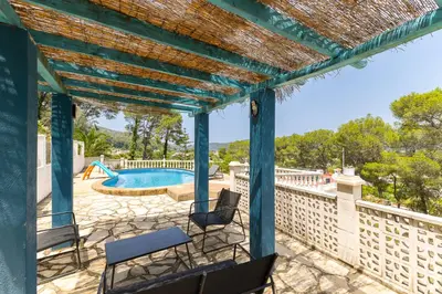 a blue pergola with chairs and a swimming pool at Chalet Barraca d 'Aigües Vives in Barraca de Aguas Vivas