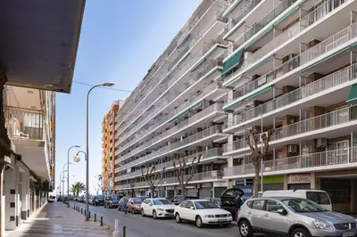 a street with cars parked in front of a large building at Levante, 1-N in Cullera