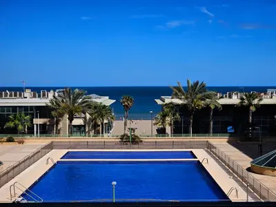 a large blue swimming pool with a view of the beach at Apartamento Brisa Patacona in Valencia