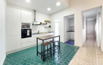 a kitchen with white cabinets and a table with stools at Gorgeous Home In Llaurí With Wifi in Llaurí