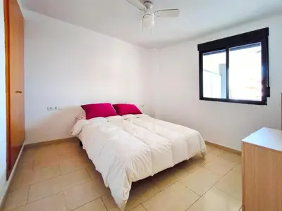 a white bedroom with a large bed with red pillows at Apartamento con Terraza junto al Mar en Moncofa in Moncófar