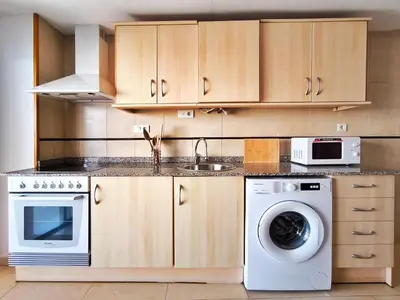 a kitchen with a washing machine and a microwave at Apartamento con Terraza junto al Mar en Moncofa in Moncófar