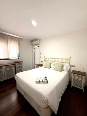 a bedroom with a large white bed and a window at Apartment 100m from the beach in Cullera