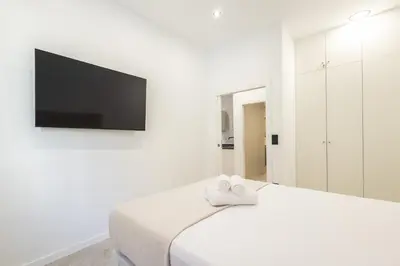 a white bedroom with a bed and a flat screen tv at Arm Suites by Concept Flats in Valencia