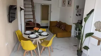 a living room with a table and yellow chairs at Sueños en la playa in Valencia