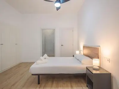 a bedroom with a large white bed and a table at Central Apartment in Benimaclet 2 in Valencia