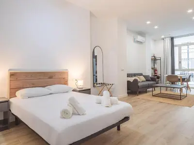 a white bedroom with a large bed and a living room at Central Apartment in Benimaclet 2 in Valencia
