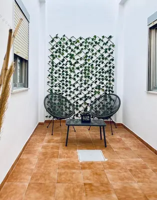 two chairs and a table in a room with a wall at Acogedora casa familiar de 4 habitaciones y gran terraza a metros de la playa in Puerto de Sagunto
