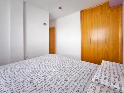 a bedroom with a bed and a wooden cabinet at Apartamento con terraza en Playa Grau de Moncofa in Moncófar