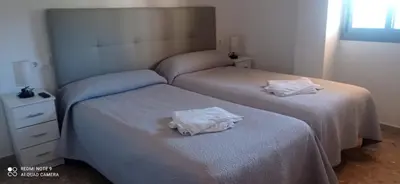 two beds in a bedroom with white towels on them at Apartamento Cullera Playa in Cullera
