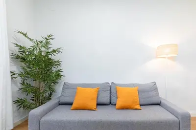 a gray couch with two orange pillows in a living room at Beachside Apartment Valencia Ideal for Digital Nomads in Valencia