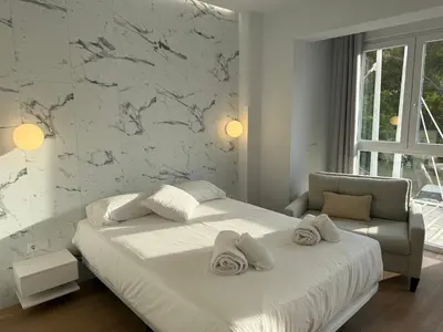 a white bedroom with a bed and a chair at Design and style next to Playa de Valencia in Valencia