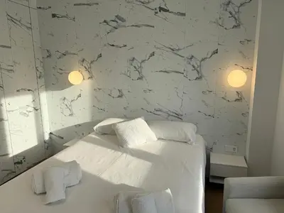 a bedroom with a white bed and a marble wall at Design and style next to Playa de Valencia in Valencia
