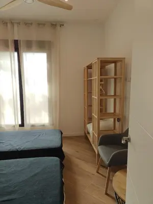 a bedroom with a bed and a chair and a cabinet at Eliving - Apartment BioPark City Center & Airport in Valencia