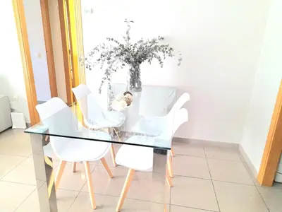 a glass dining room table with white chairs and a vase of flowers at BEACH VALENCIA LUXURY D15-21 Apartment with terrace and sea views with two rooms in Valencia