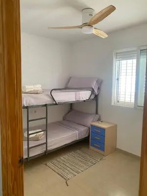 a room with two bunk beds and a ceiling fan at Encantador apartamento con terraza en la Playa de Moncófar in Moncófar