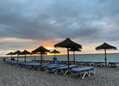 a line of chairs and umbrellas on a beach at kalma in Moncófar