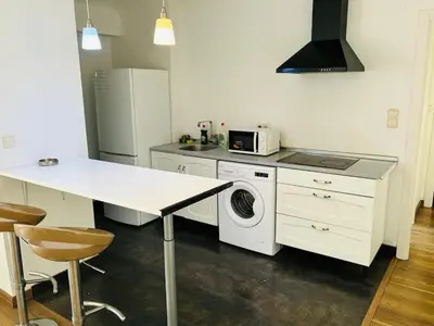 a kitchen with a washing machine and a table at Atico con vistas al atardecer admitanse mascotas in El Puig