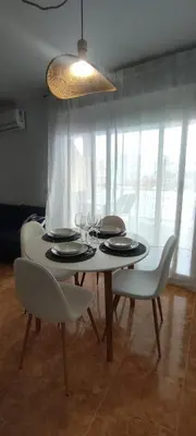 a dining room table with white chairs and a light at Magnifico apartamento de playa in Moncófar