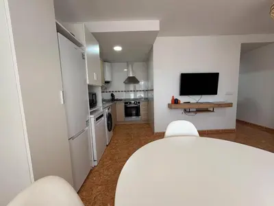 a living room with a television and a kitchen at Magnifico apartamento de playa in Moncófar