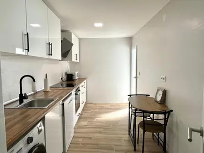 a kitchen with a sink and a wooden table at El sitio de Ana in Burriana