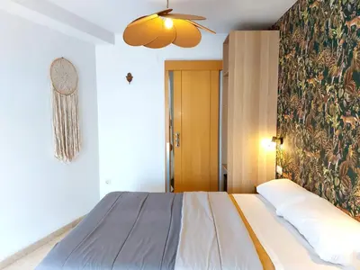 a bedroom with a bed and a wall with a painting at ATTIC ROOMs VALENCIA in Valencia