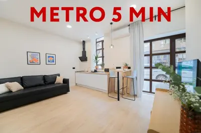 a living room with a black couch and a kitchen at Apartments LEON GABRIEL MIRÓ in Valencia