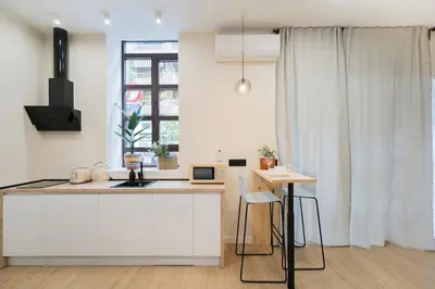 a kitchen with white cabinets and a table and a window at Apartments LEON GABRIEL MIRÓ in Valencia