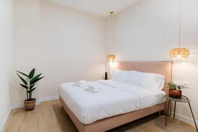 a bedroom with a large white bed with two lamps at Apartments LEON PARE RICO in Valencia
