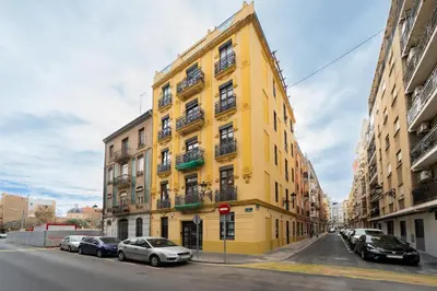 a yellow building on a street with parked cars at Apartments LEON PARE RICO in Valencia