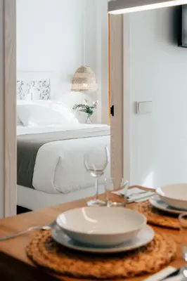 a table with a plate and glasses on top of a bed at Valencia Living Suites in Picanya