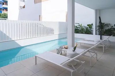 a swimming pool with two tables and a table with a bottle of wine at Valencia Living Suites in Picanya