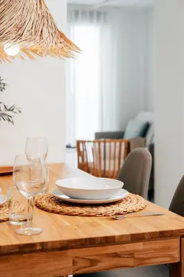a wooden table with a plate and wine glasses on it at Valencia Living Suites in Picanya