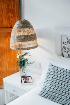 a lamp on a bed with a vase of flowers on a table at Valencia Living Suites in Picanya