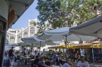 people sitting at tables under white umbrellas on a street at SingularStays San Vicente in Valencia