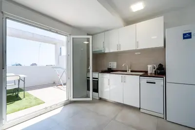 a kitchen with white cabinets and a large window at Apartamento Ciudad de las Ciencias con Terraza in Valencia