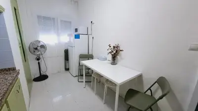 a white kitchen with a table and chairs and a refrigerator at 3 bedroom apartment with a terrace 50 steps from the Nules beach in Mascarell