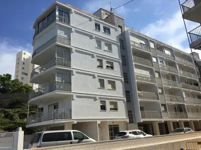 a tall white building with cars parked in front of it at Fantásticas vistas al mar en el Faro in Faro de Cullera