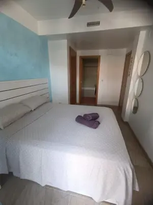 a bedroom with a white bed with a purple towel on it at Puzol beach penthouse in Playa de Mar