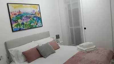 a white bed with pillows in a room with a window at ESPECIAL FALLAS 25 MINUTOS VALENCIA PLAYA in Puerto de Sagunto