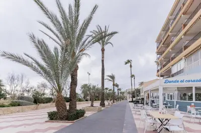 a walkway with tables and palm trees in front of a building at Fabuloso Piso Playa Canet de Bereguer Alquiler minimo 11 noches llamar al 64039uno856 in Canet de Berenguer