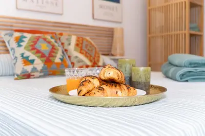 a plate of food and a glass of orange juice on a bed at Casa Ambrosia in Valencia