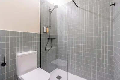 a bathroom with a shower with a toilet and a glass door at Blue City Apartments in Valencia
