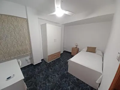 a white bedroom with a bed and a cabinet at piso tres habitaciones in Valencia