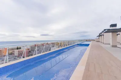 a swimming pool on the roof of a building with the ocean at Seaview Apartment in Canet with Rooftop Pool in Canet de Berenguer