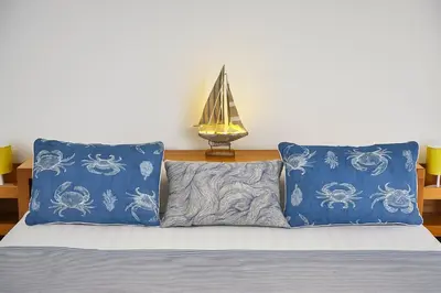 a bed with two blue pillows and a sailboat at Valencia Beach Home 21 in Valencia