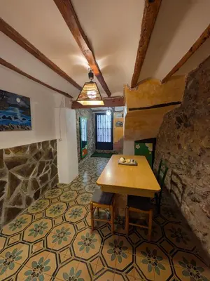 a room with a table and a stone wall at Casa rural El Mestre in Alcudia de Veo