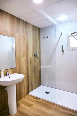 a bathroom with a glass shower and a sink at V Pension & Suites in Burriana