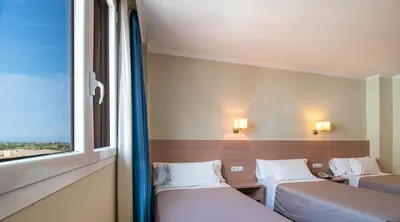 two beds in a room with a window at Hotel Alba in Puzol