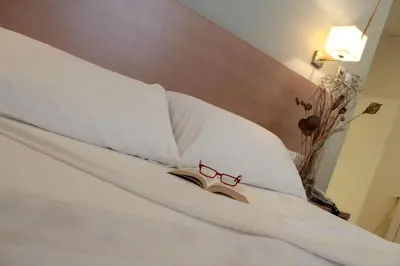 a bed with a book and glasses on it at Hotel Alba in Puzol